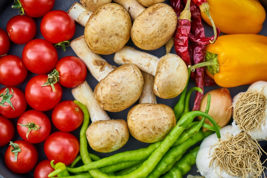 A vibrant assortment of fresh vegetables and mushrooms arranged in a flat lay.